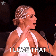 a woman in a white dress says " i love that " in front of a microphone