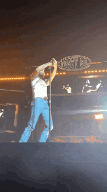 a man is singing into a microphone in front of a sign that says posty co.