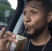 a man is drinking from a plastic cup with a straw .