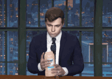 a man in a suit and tie holding a bottle of lysol hand sanitizer