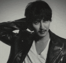 a man with a mustache wearing a leather jacket and a white shirt