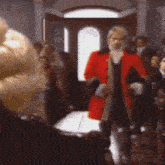 a man in a red coat is standing in front of a crowd of people .