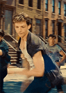 a man in a blue shirt is running down a street