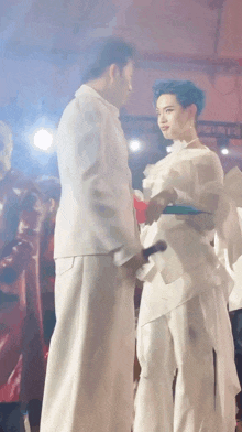 a man and a woman are standing next to each other in front of a crowd .