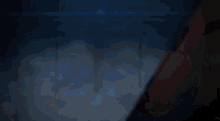 a person is holding a sword in a dark room with a blue light behind them