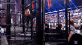 a wrestler is chained to a cage during a wrestling match while a referee watches .