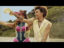a man and a woman are standing on a beach and the woman is holding the man 's arm