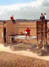 a man in a red shirt sits on top of a wooden structure
