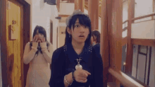 two girls are standing in a hallway and one is pointing