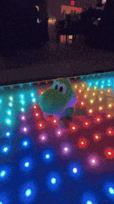 a stuffed yoshi toy is dancing on a dance floor
