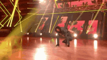a woman is kneeling down on a dance floor in front of a stage .