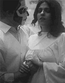 a black and white photo of a man and a woman holding hands .
