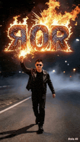 a man in a leather jacket is walking down a road holding a torch in front of a sign that says 90r