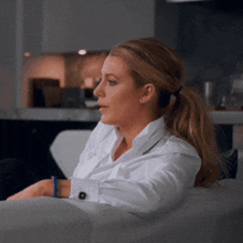 a woman in a white shirt is sitting on a white couch