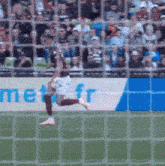 a soccer player is running towards a goal with a met.fr banner in the background