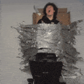 a man is taped to a wall with duct tape and a chair in front of him