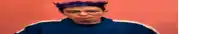 a man with purple hair is wearing a blue jacket and making a face .