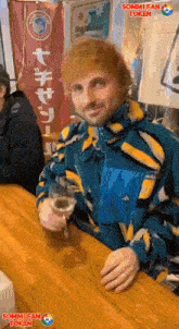 a man in a colorful jacket holds a glass of wine in front of a sommi fan token sign