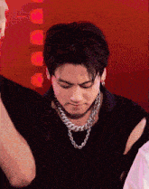 a young man wearing a black shirt and a chain around his neck