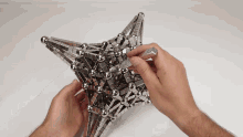 a person is playing with a star made out of metal balls