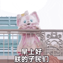 a pink teddy bear is standing on a balcony and holding a cookie .