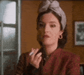 a woman in a headband is smoking a cigarette .