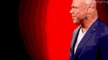 a man in a suit is standing in front of a red background .