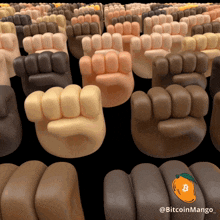 a bunch of fist shaped objects with a sticker that says bitcoin mango