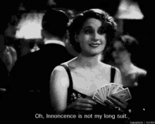 a black and white photo of a woman holding a fan of cards with the caption oh innocence is not my long suit