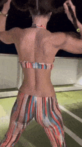 the back of a woman in a bikini and striped pants