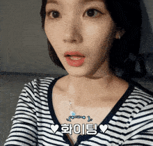 a close up of a woman 's face with a striped shirt and a necklace that says ' uwjk '