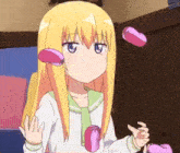 a girl with blonde hair and blue eyes is holding two pink hearts in her hands