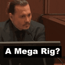 a man sitting in front of a computer with the words " a mega rig " behind him