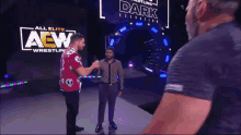 two men are standing in front of a sign that says aew wrestling