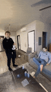 a man wearing a mask sits on a couch while another man stands behind him