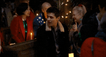 a group of people sitting around a table with candles in front of them
