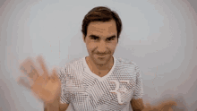 a man in a striped shirt is waving his hands in front of a white wall .