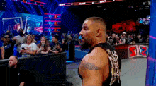 a man in a black tank top stands in front of a crowd at a wrestling match