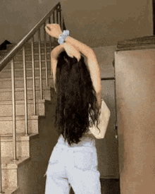 a woman with long black hair is standing on a set of stairs with her arms outstretched .