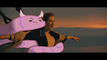 a woman is flying through the air with a pink cat on her shoulders