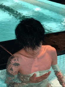 a man with a tattoo of a fish on his shoulder is swimming in a pool