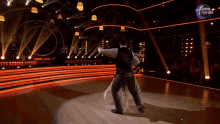 a man and woman are dancing on a stage with dancing brasil written on the wall behind them