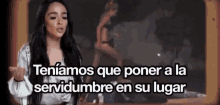 a woman is standing in front of a sign that says tener a la servidumbre en su lugar