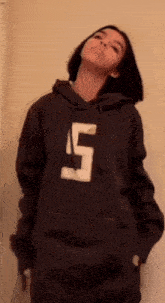 a girl is wearing a hoodie with the number 5 on it