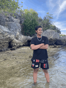 a man wearing bulls shorts and a black shirt stands in the water