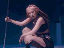 a woman in a black top and skirt holds a pole in her hand