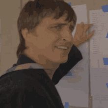 a man with a backpack is looking at papers taped to a wall including one that says " a " on it