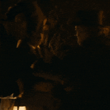 a man in a top hat shakes hands with another man in a dark room