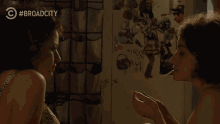 a woman spraying another woman 's face with broad city written on the bottom of the screen