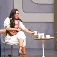 a woman is sitting on a chair holding a cup of coffee .
